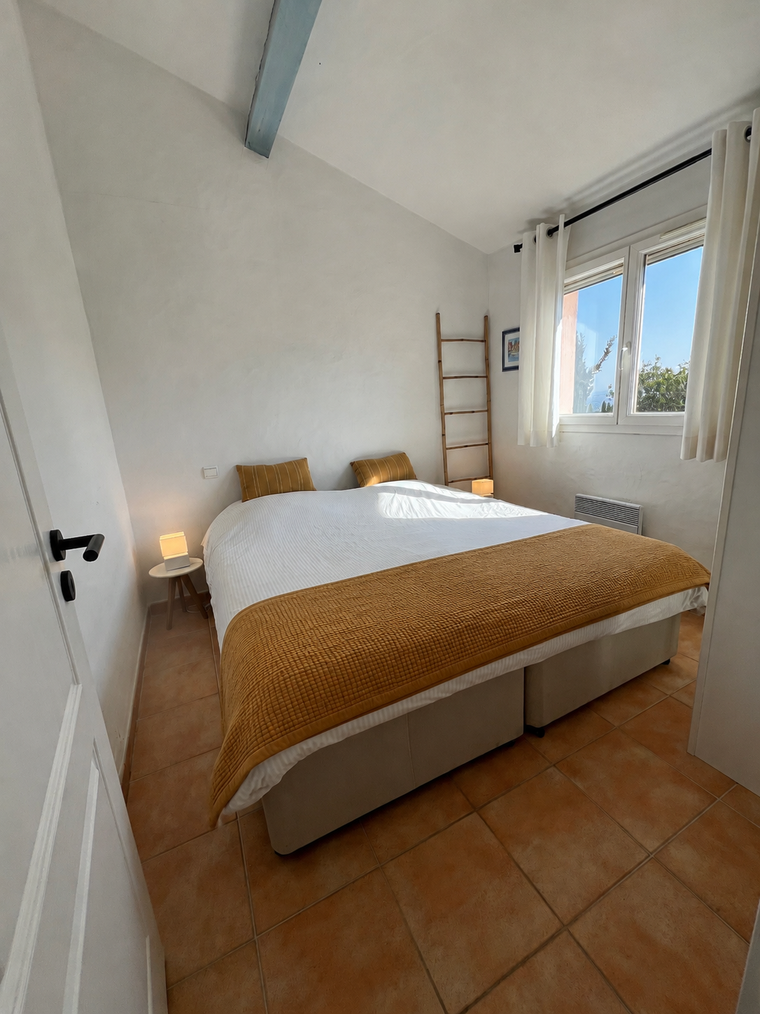 Tweede slaapkamer met dubbel bed en raam op de tuin